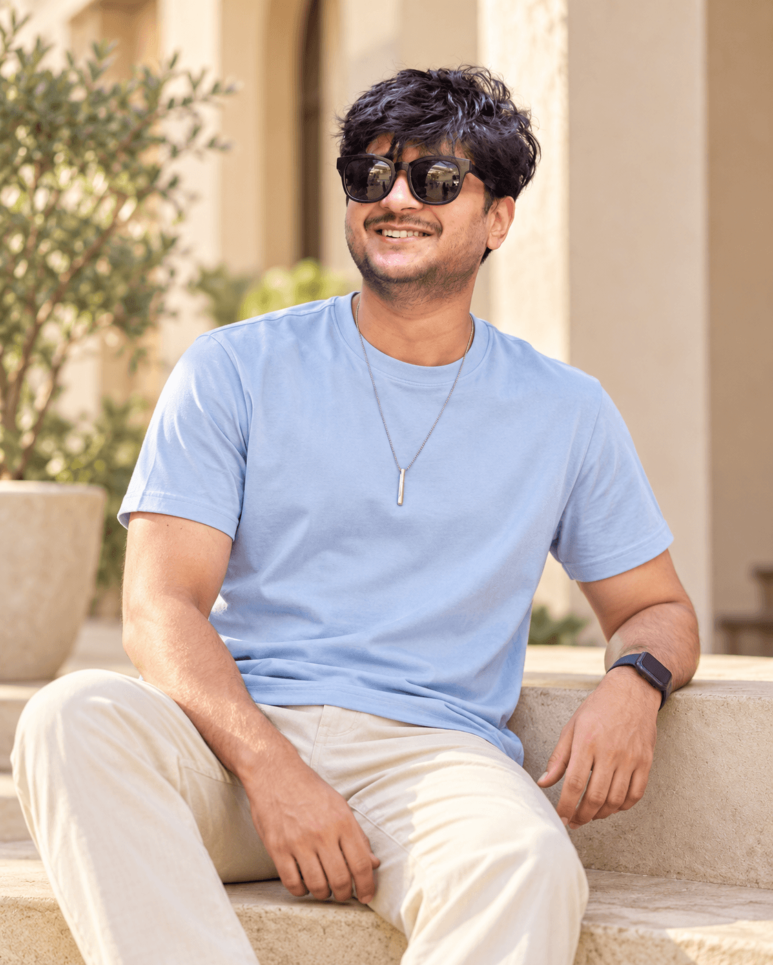 Dipesh wearing a light blue T-shirt and cream trousers