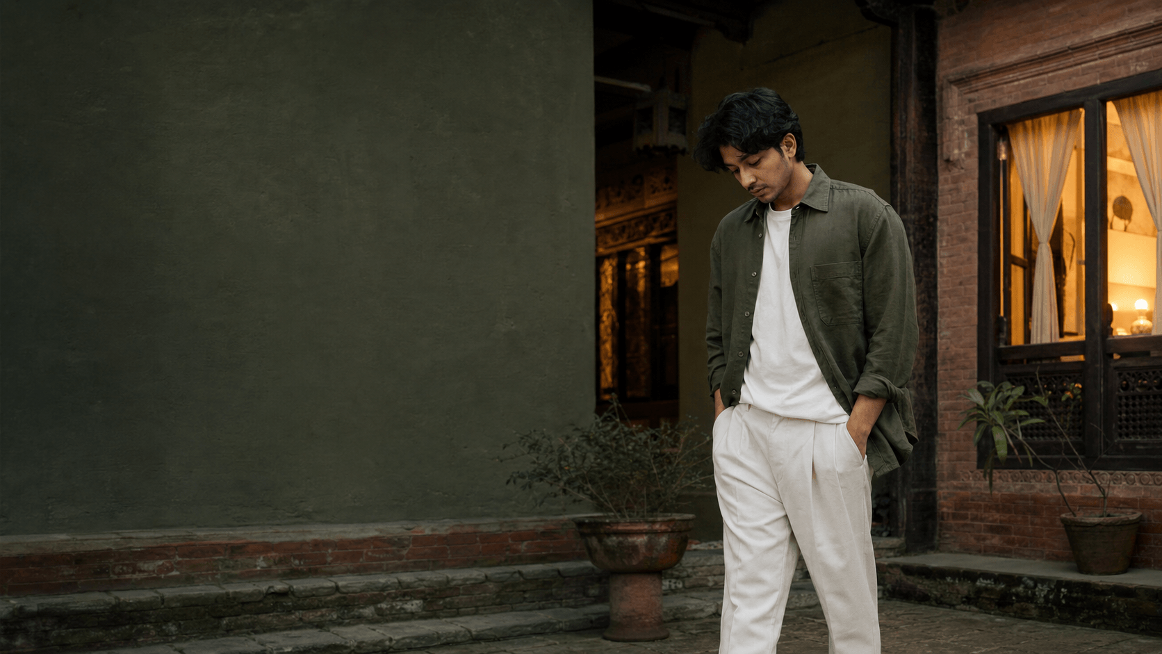 Man in an olive overshirt in a quiet Kathmandu courtyard at dusk